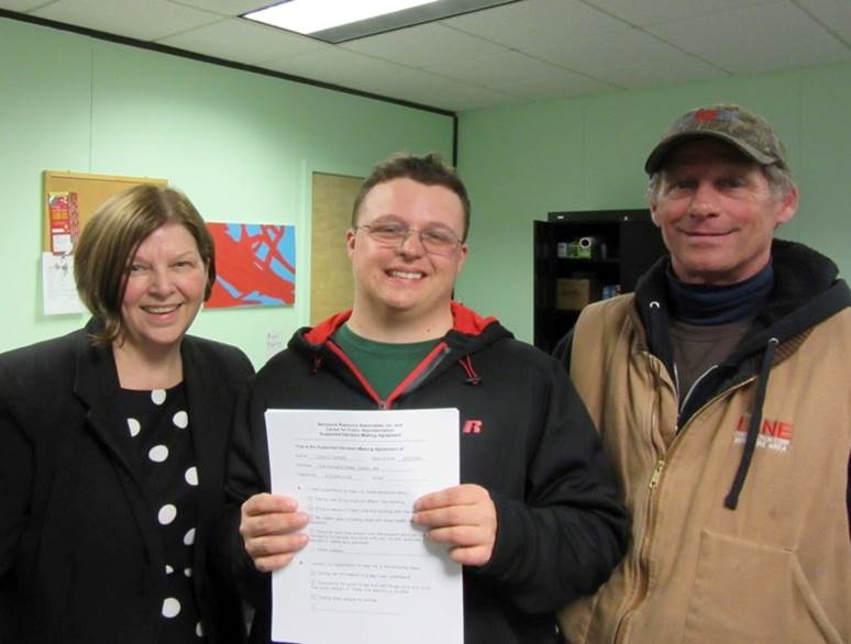 Cory holding SDM agreement posing with parents.