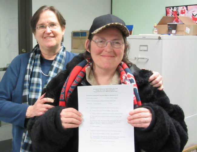 Photo of Kathy posting with one of her supporters and her signed SDM agreement